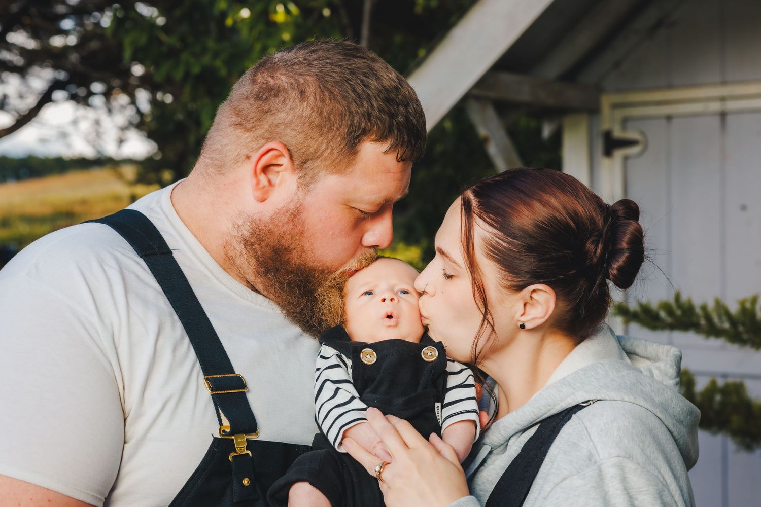 Parents kissing their baby during warm family photo session