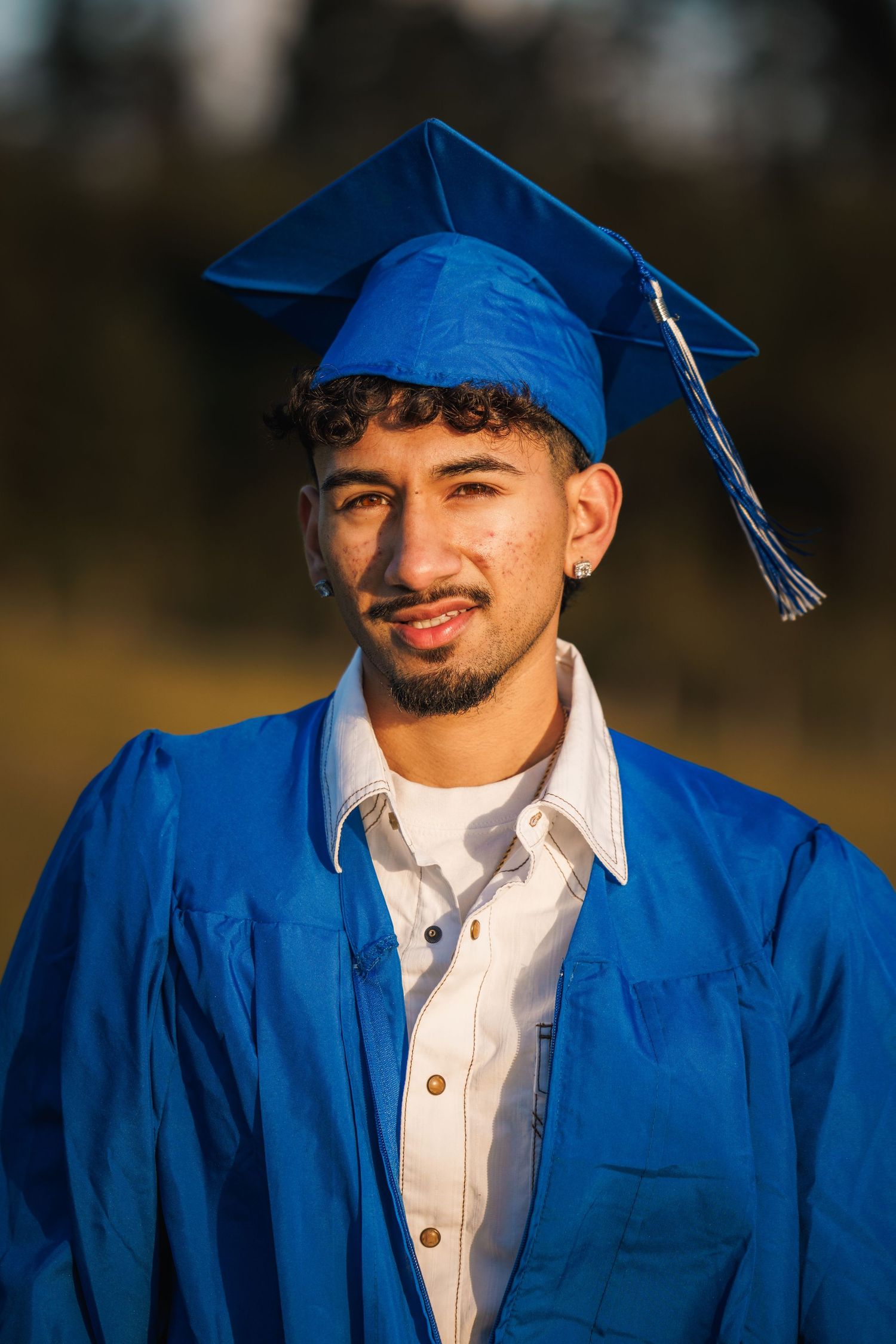 High school graduate wearing a blue cap and gown during a graduation portrait session.