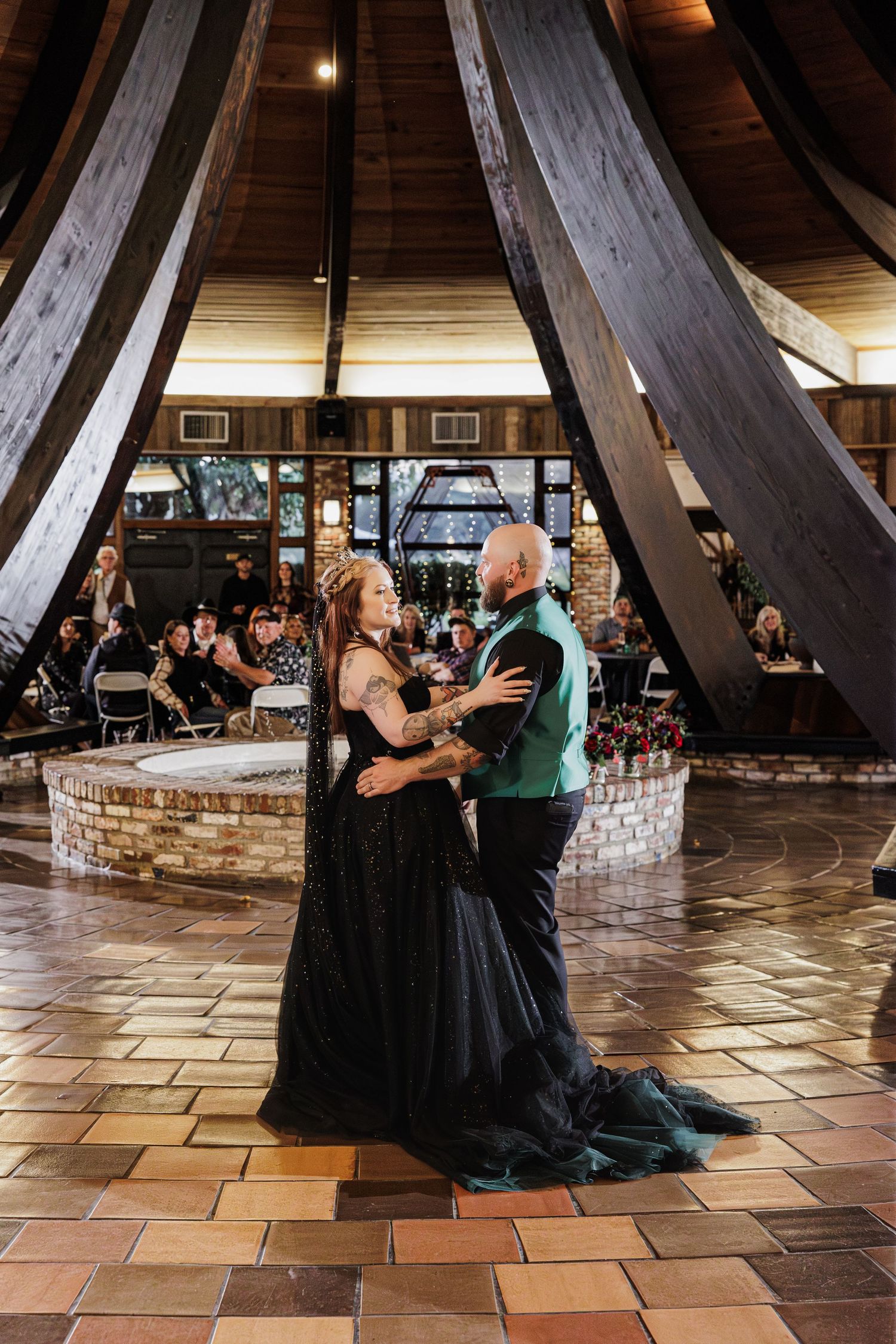 Newlyweds share their first dance beneath dramatic drapery at their wedding reception.