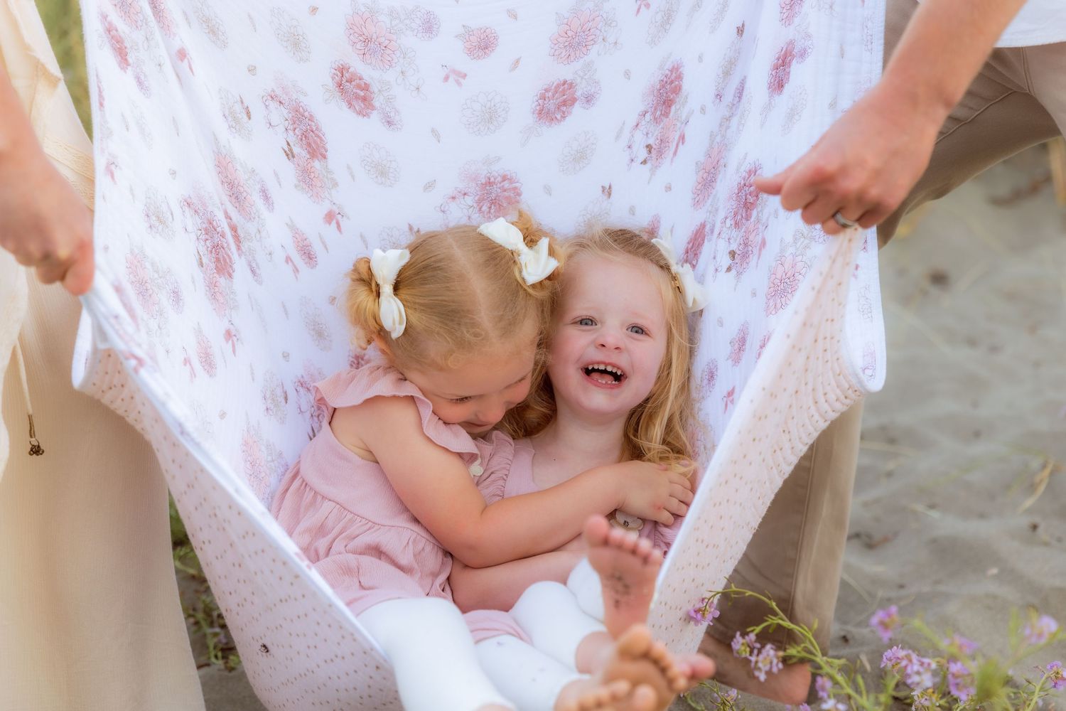 Two young children hugging beneath a floral blanket during family session