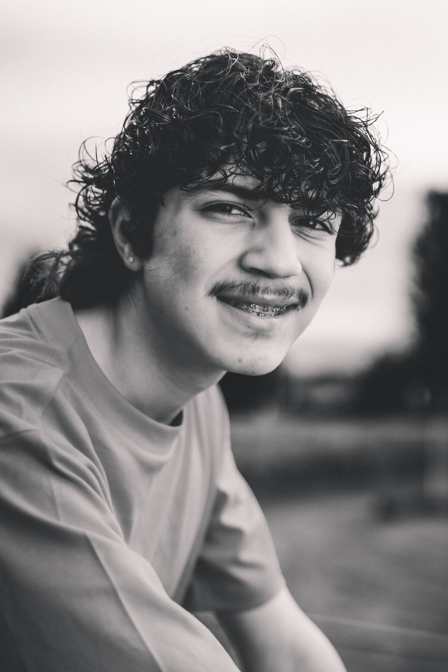 Black and white close-up portrait of a smiling high school senior outdoors.