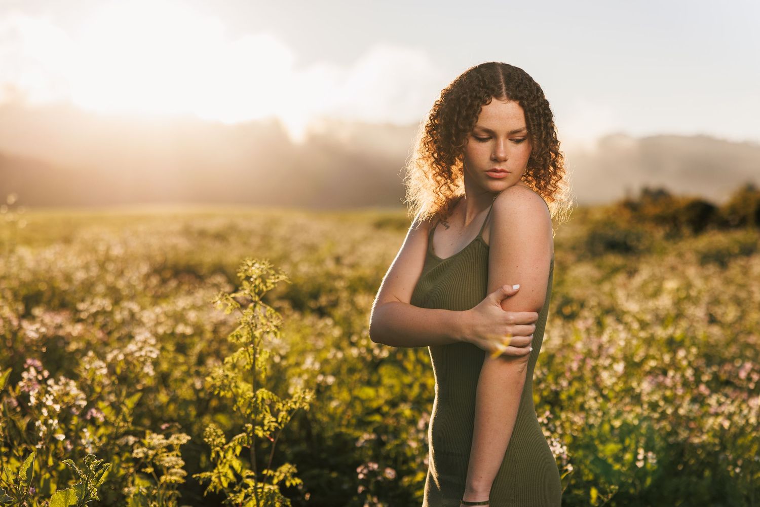 High school senior posing among wildflowers during a warm golden-hour outdoor portrait session.