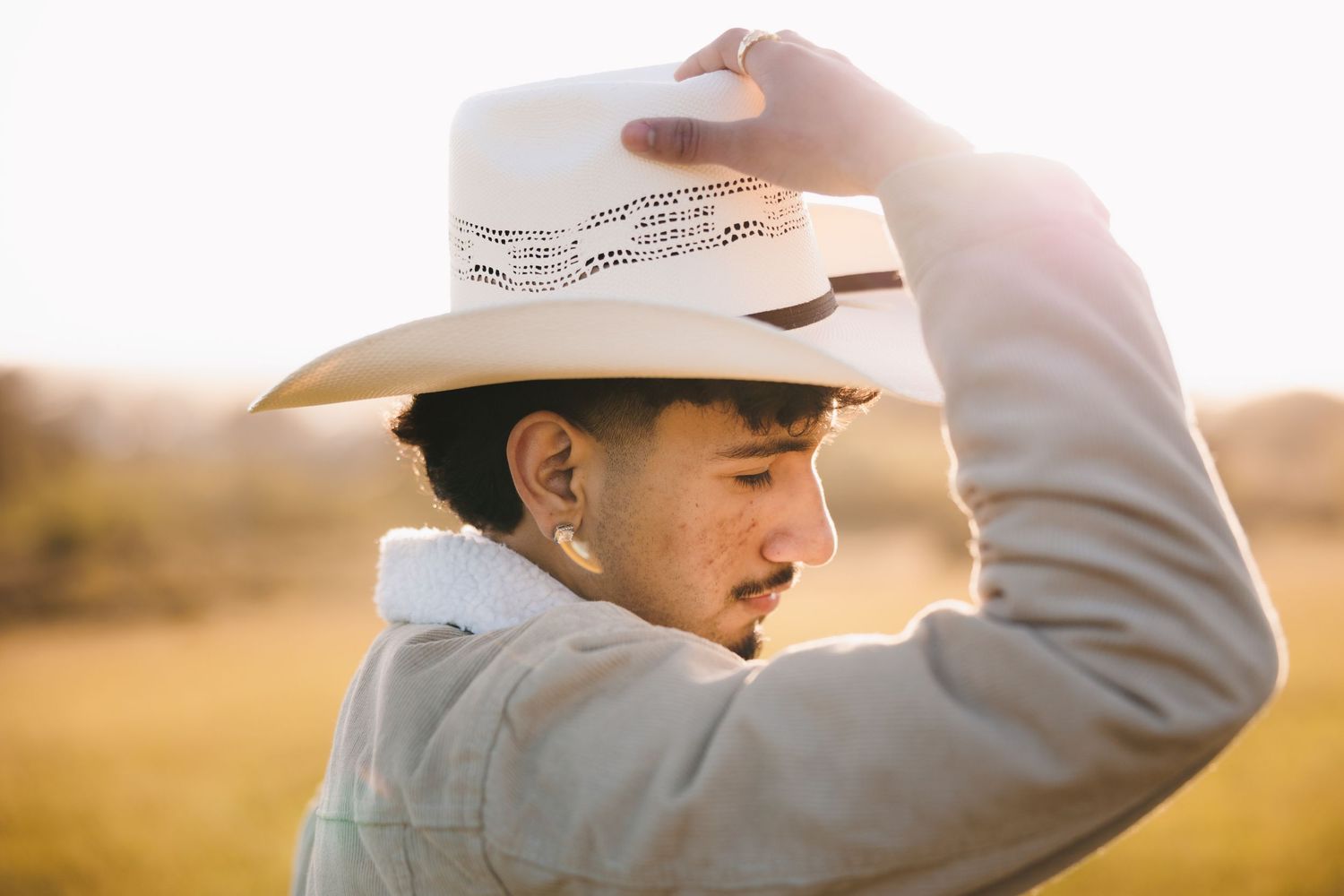 High school senior wearing a cowboy hat during a warm golden-hour senior portrait session.