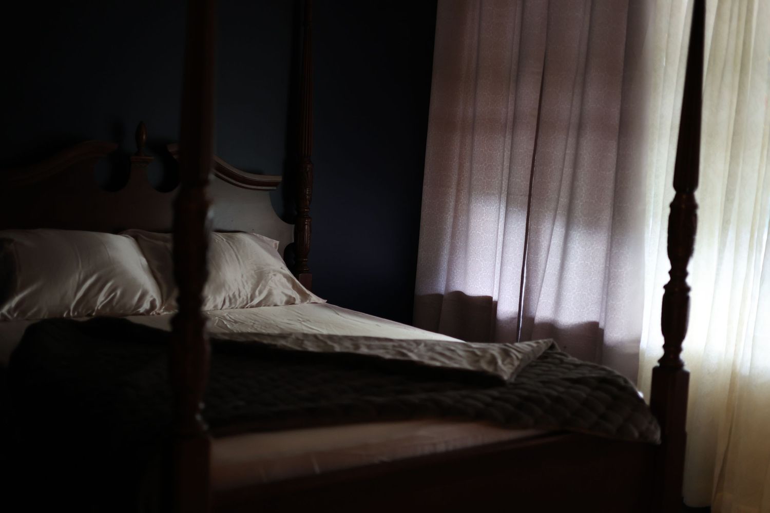 Moody boudoir studio bedroom with a four-poster bed, soft linens, and window light in Putney, Vermont