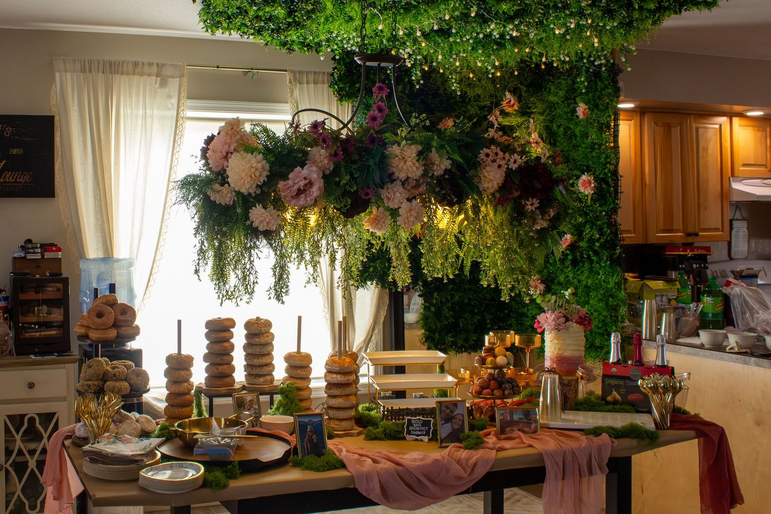 Elegant dessert table decorated with hanging floral arrangement of pink flowers and greenery indoors.