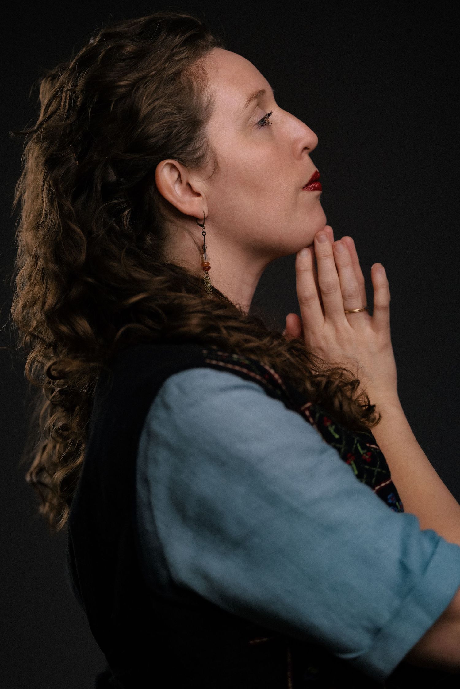 Artistic portrait featuring dramatic light, thoughtful expression, and a minimalist black background.