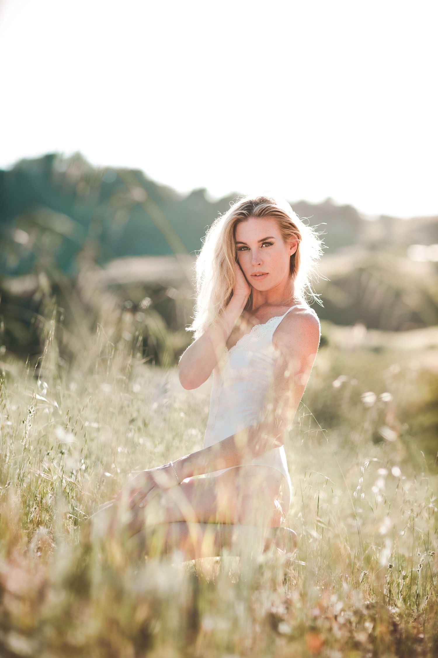 Natural light portrait of a woman standing in a sunlit field during golden hour.