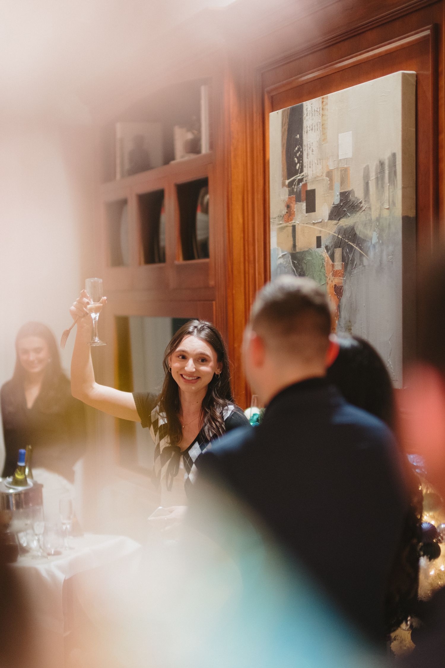 Event storytelling photography capturing guests sharing a toast during an intimate celebration.