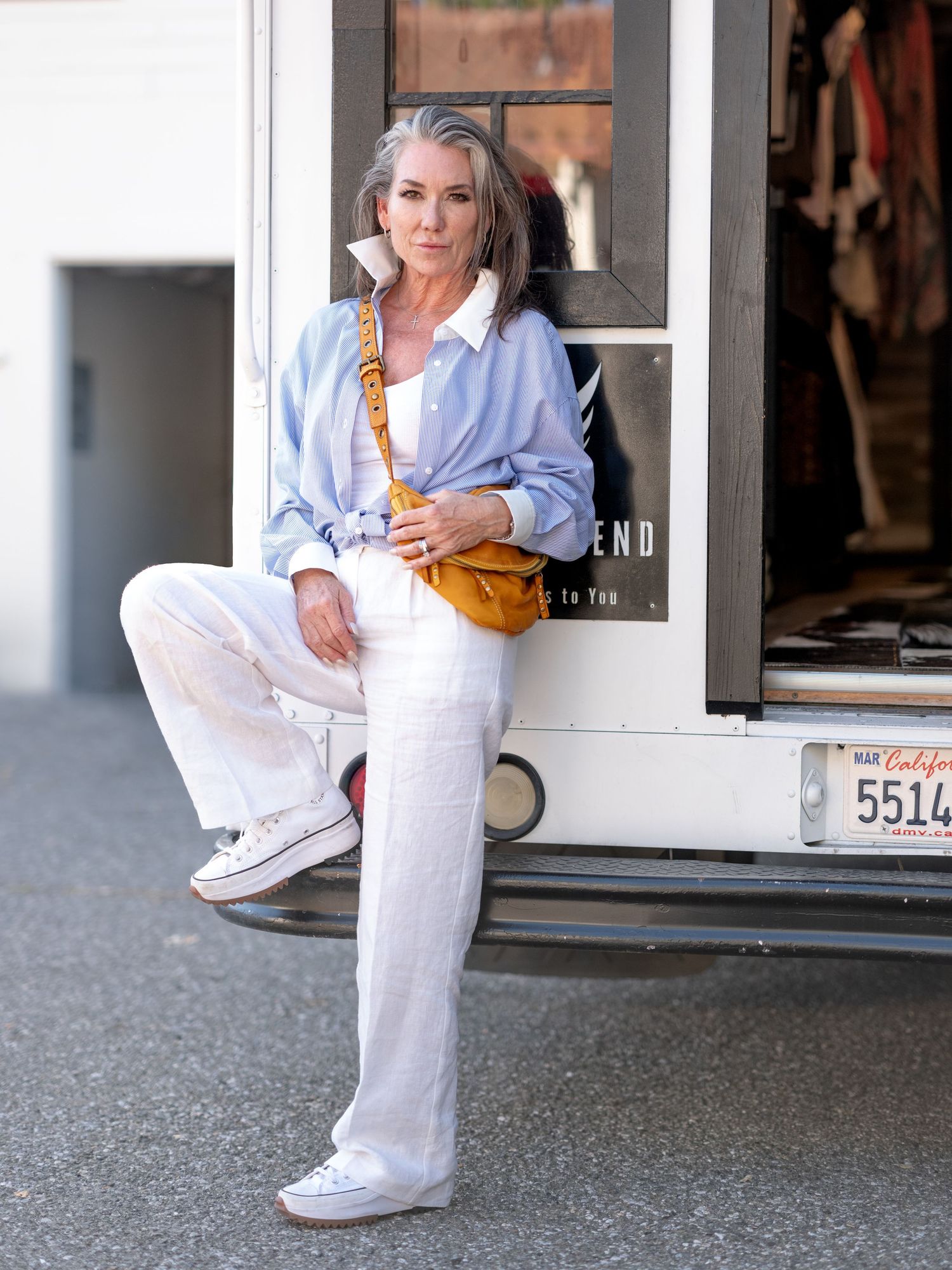 Editorial portrait of a woman seated outdoors in relaxed styling and natural light.
