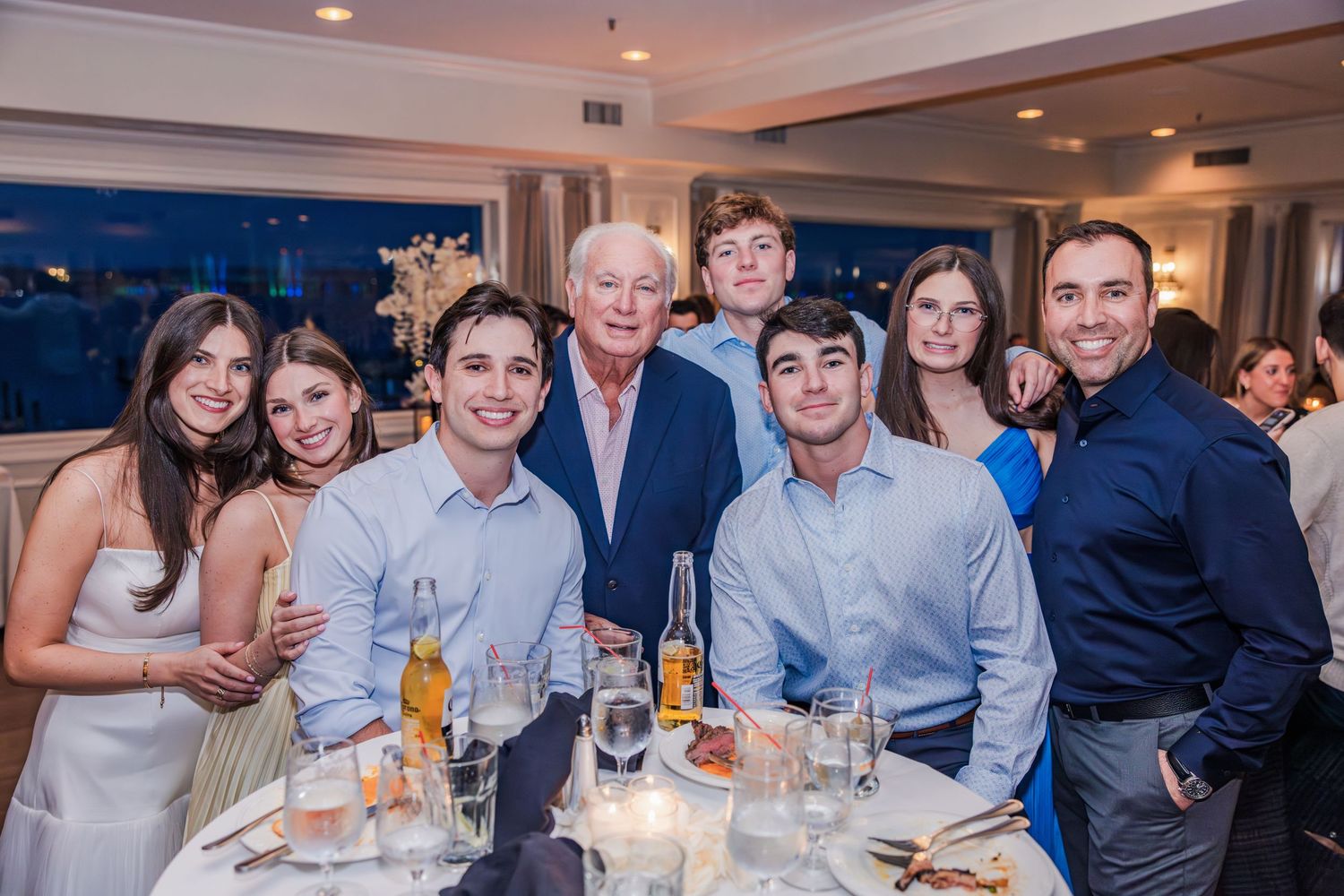 Family group smiling together at a dinner table during an evening celebration event.