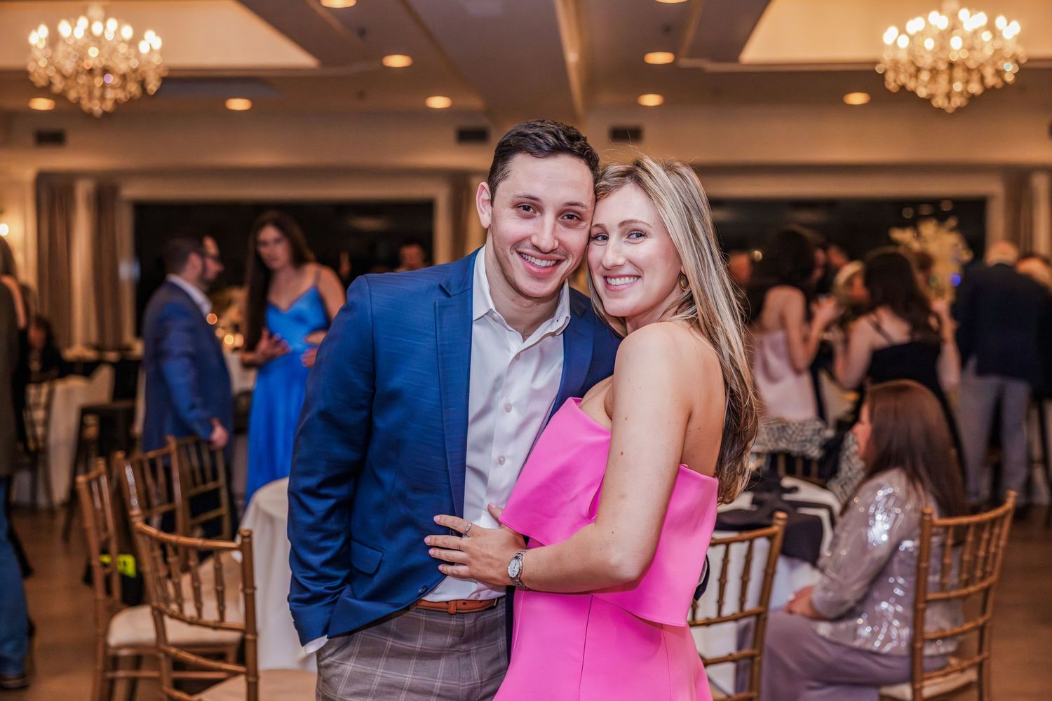Couple in formal attire embracing and smiling at an elegant indoor celebration event.