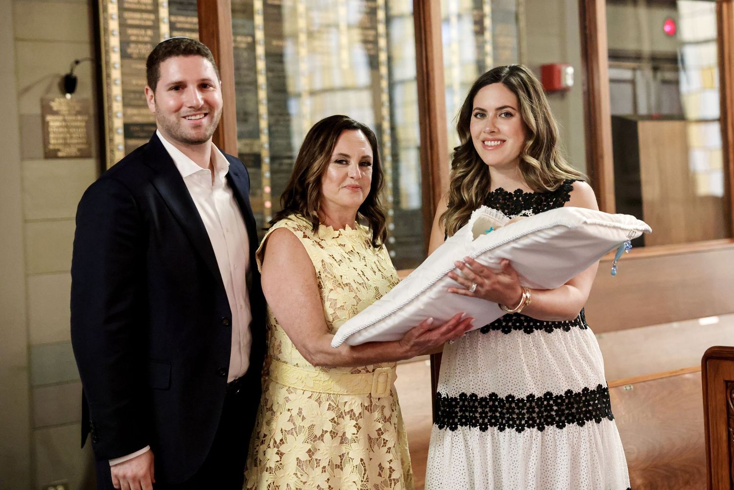 Family poses with swaddled newborn baby at a church christening ceremony.