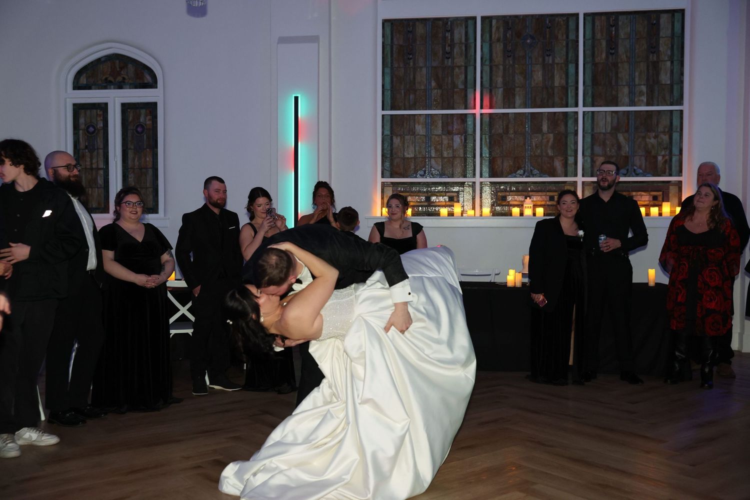 Groom dipping bride dramatically during romantic first dance at elegant wedding reception.