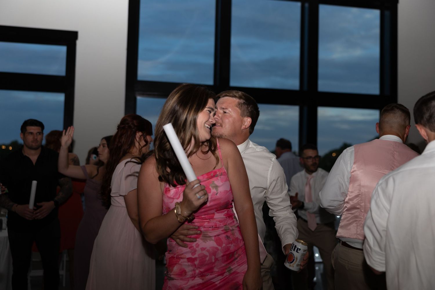 Couple sharing a romantic kiss on the dance floor during lively wedding reception celebration.