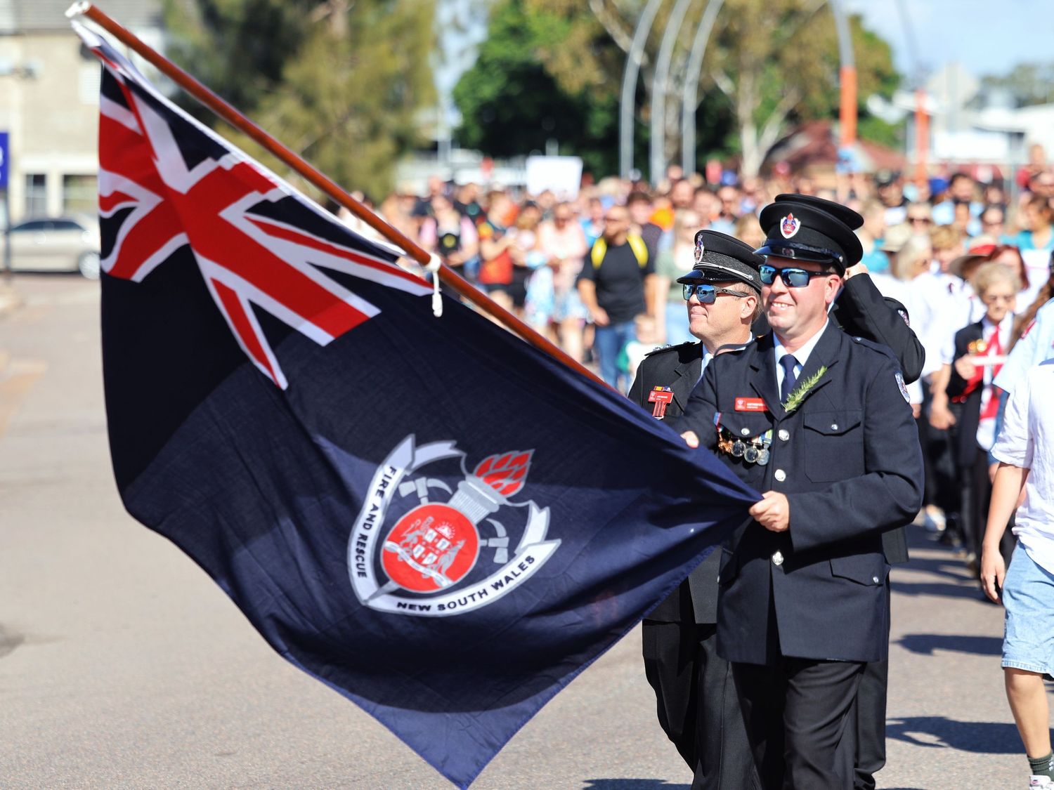 Uniformed officers carrying New South Wales flag during an ANZAC Day parade.