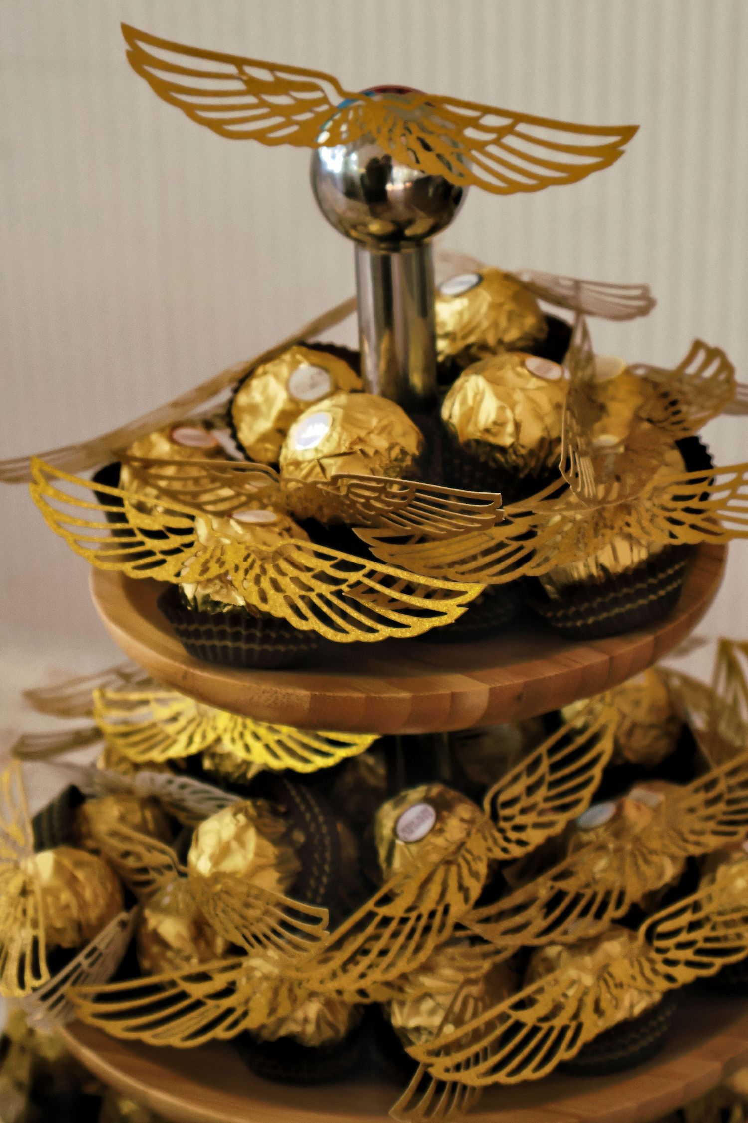 Three-tier dessert stand with Ferrero Rocher chocolates decorated as Golden Snitches with wings.