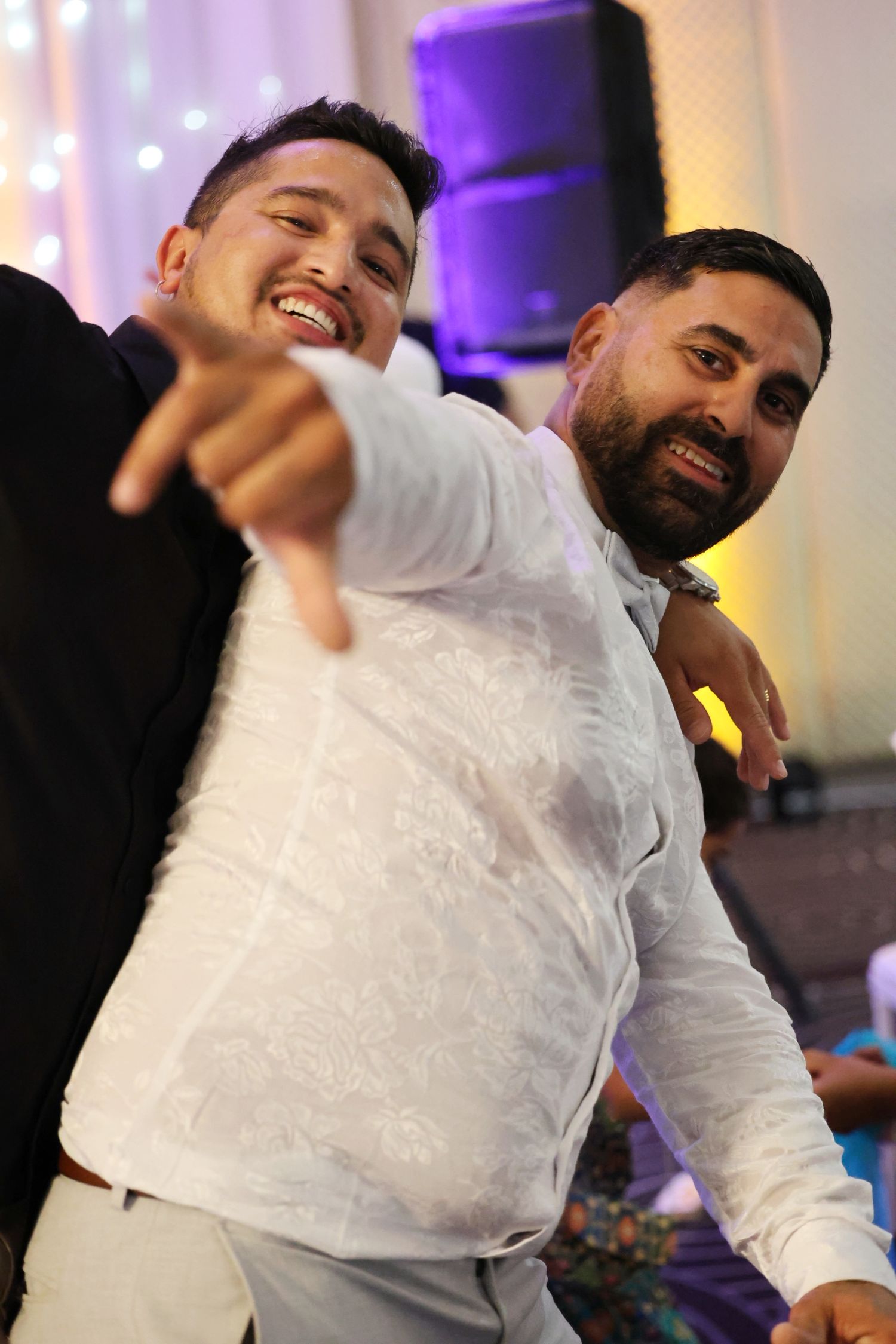 Two men smiling and posing together at a festive wedding reception party.