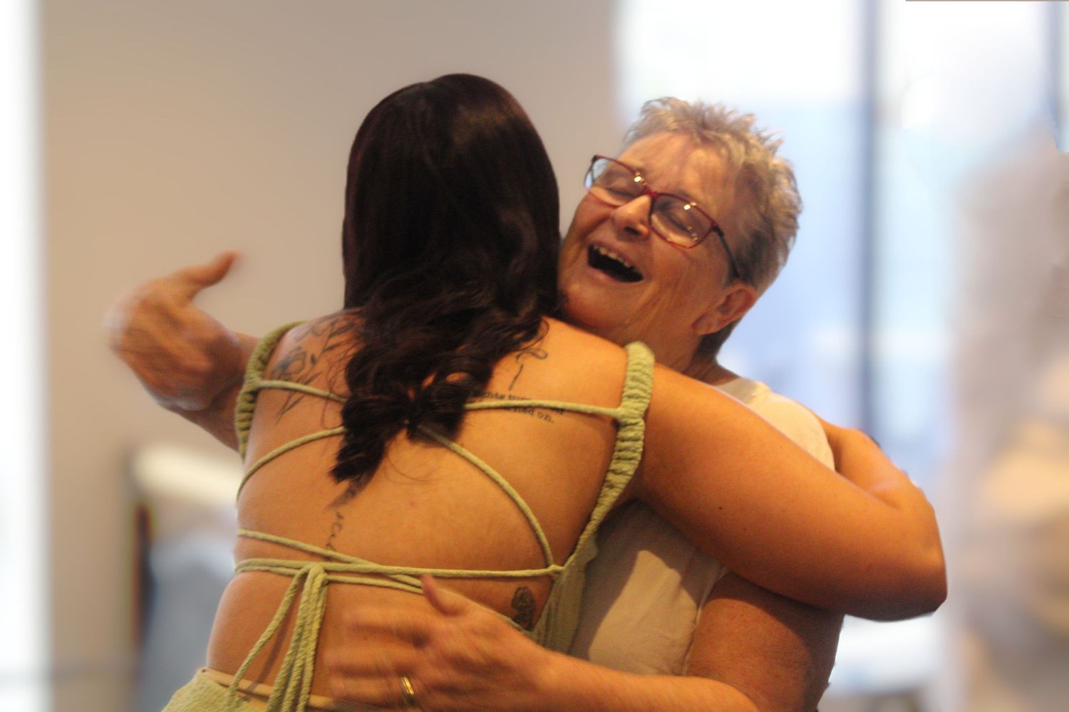 Two women sharing a warm embrace and laughing joyfully at a celebration event.