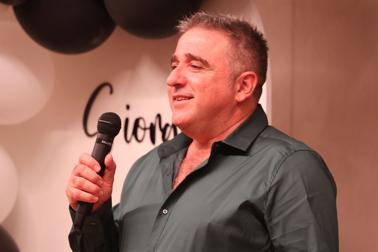 Smiling man speaking into microphone at Giorgia's birthday party event.