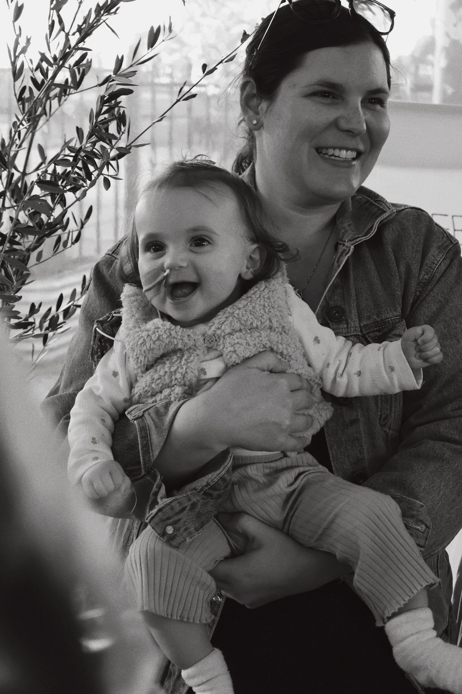 Black and white photo of smiling woman holding a laughing baby outdoors.