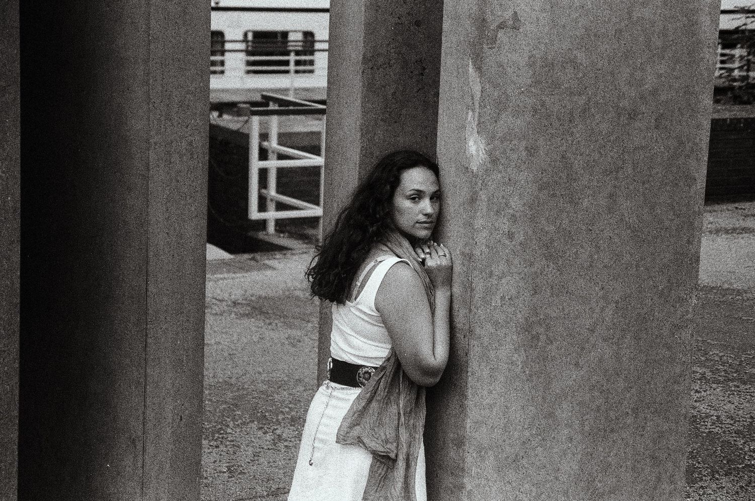 Black and white 35mm film portrait of a woman next to a wall
