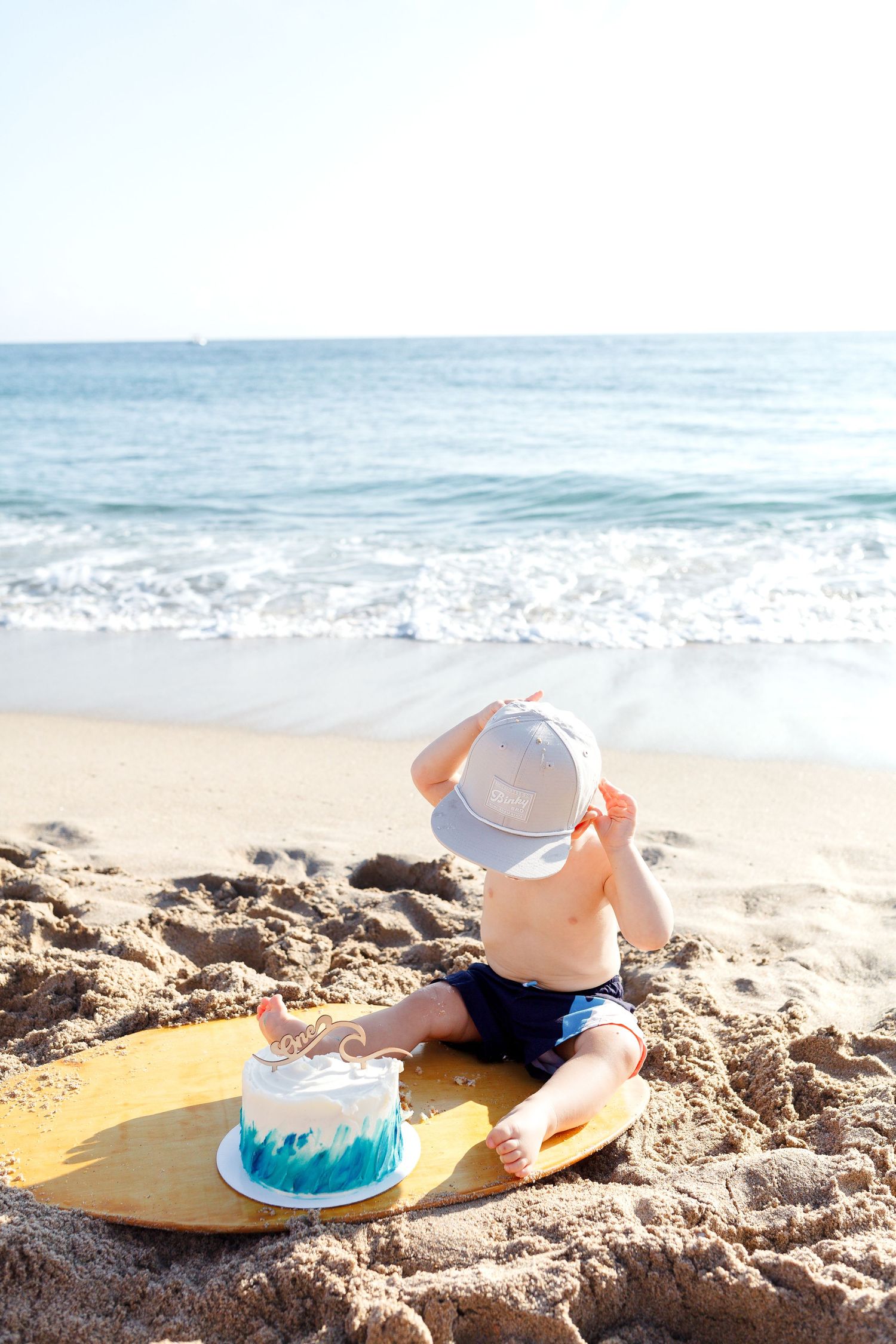baby's first birthday photoshoot on the beach with surfboard