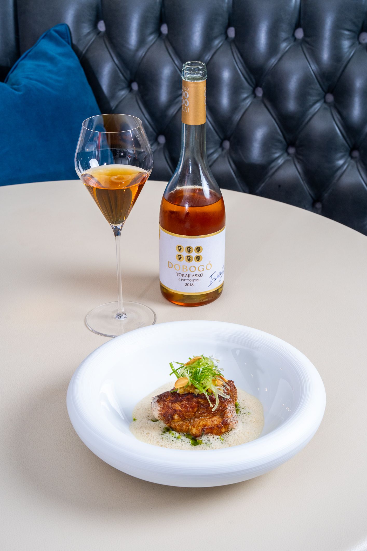 Roasted meat dish with wine pairing on a white plate beside a bottle of rose wine.