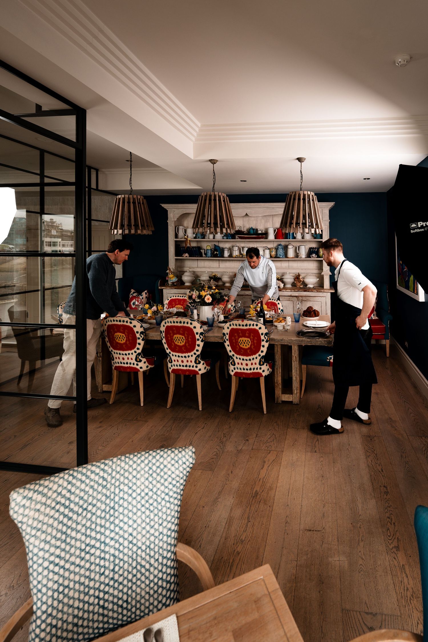 Staff setting a elegant dining table in a stylish restaurant with dark walls and wooden floors.