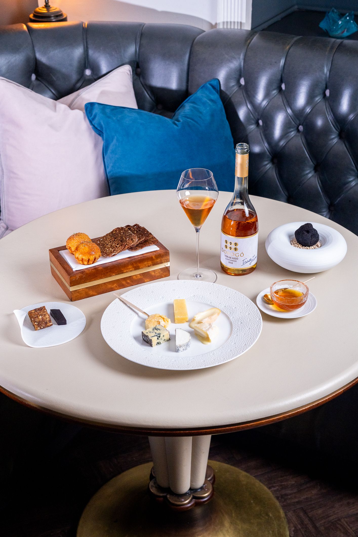Cheese board with crackers, honey, and rose wine elegantly displayed on a round table.