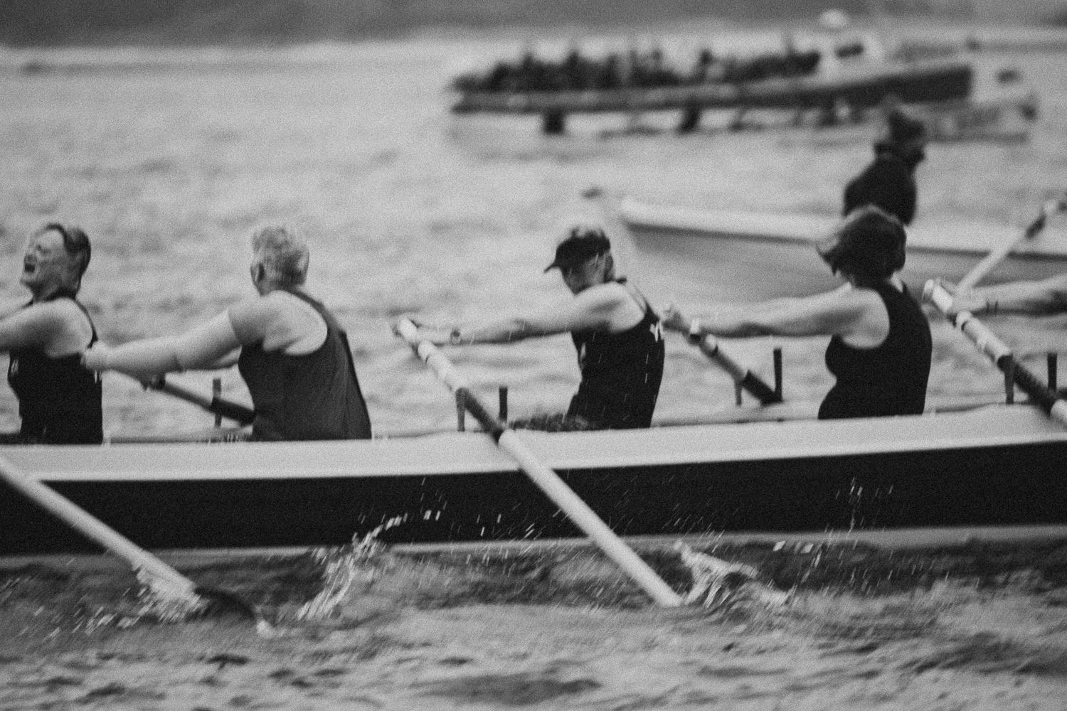 Black and white photo of a rowing team competing on open water during a race.