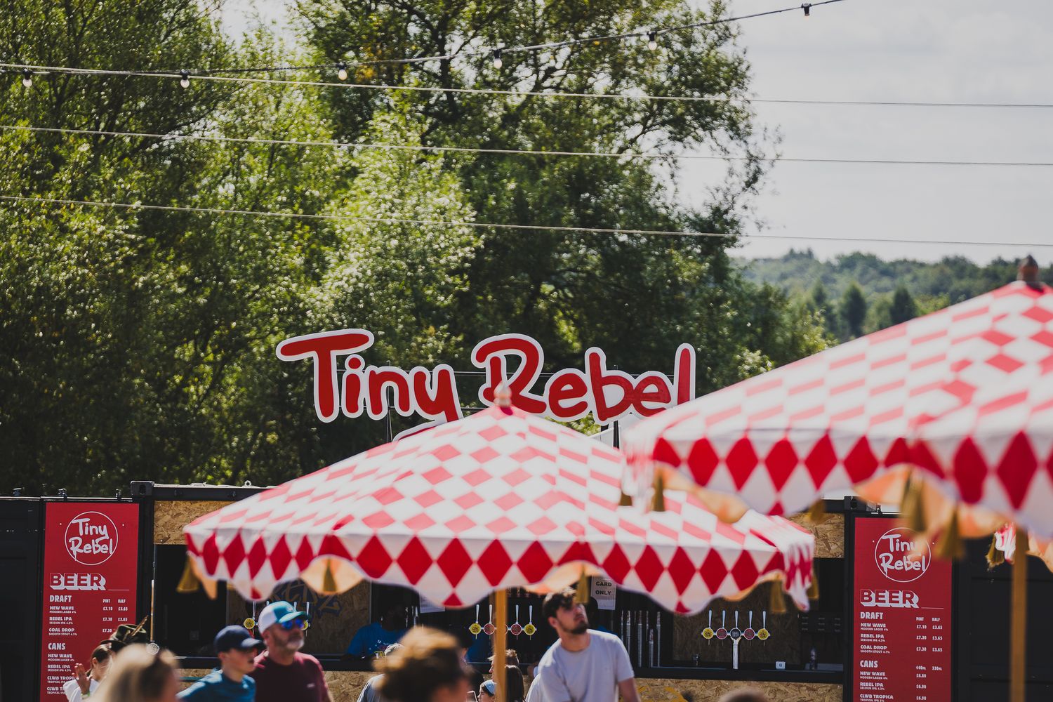 Tiny Rebel brewery tent with red and white diamond pattern at an outdoor festival.
