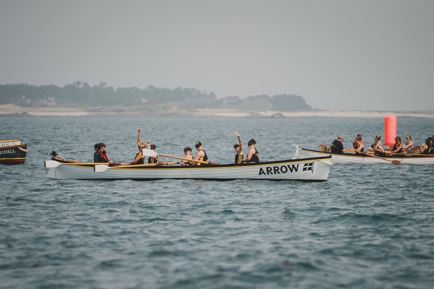 Competitors rowing the Arrow pilot gig boat during a sea race with a red buoy marker nearby.