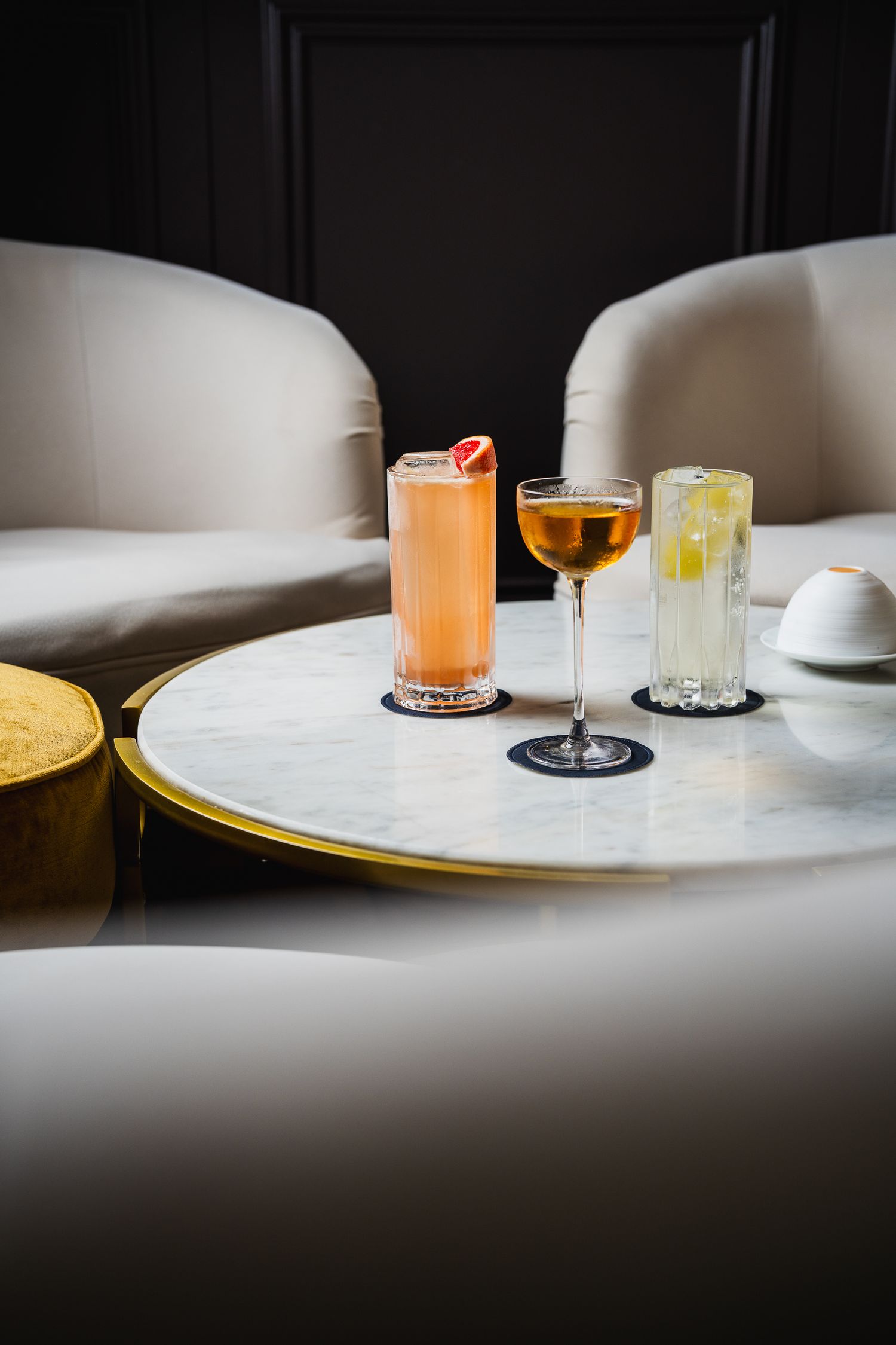 Three elegant cocktails on a marble and gold side table in a sophisticated lounge setting.