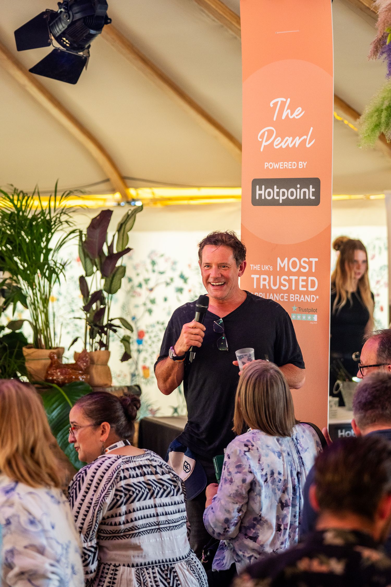 Man speaks with microphone at The Pearl powered by Hotpoint festival hospitality tent.