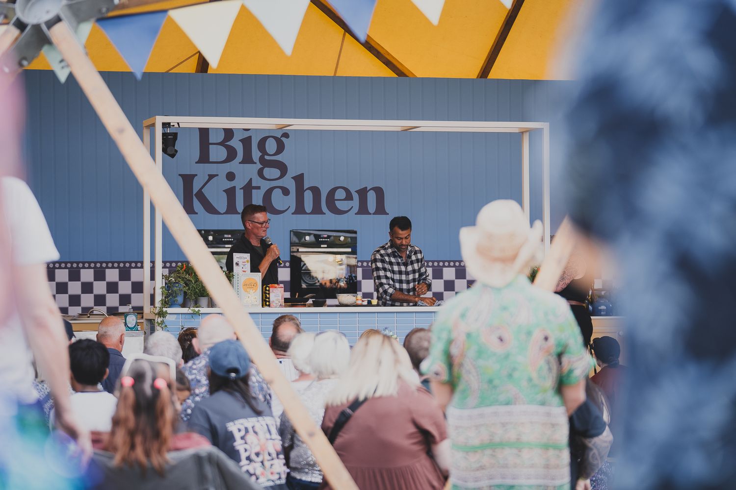 Crowd watches chefs demonstrate cooking at the Big Kitchen outdoor food festival stage.