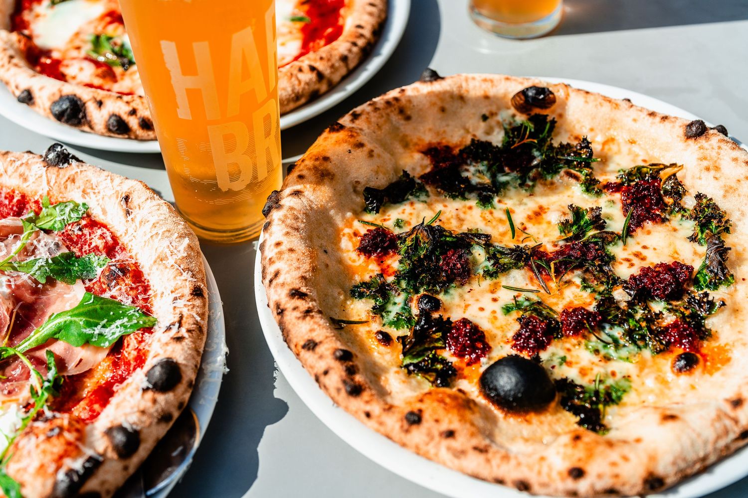 Authentic Neapolitan wood-fired pizzas with olives, herbs, and toppings served with beer.