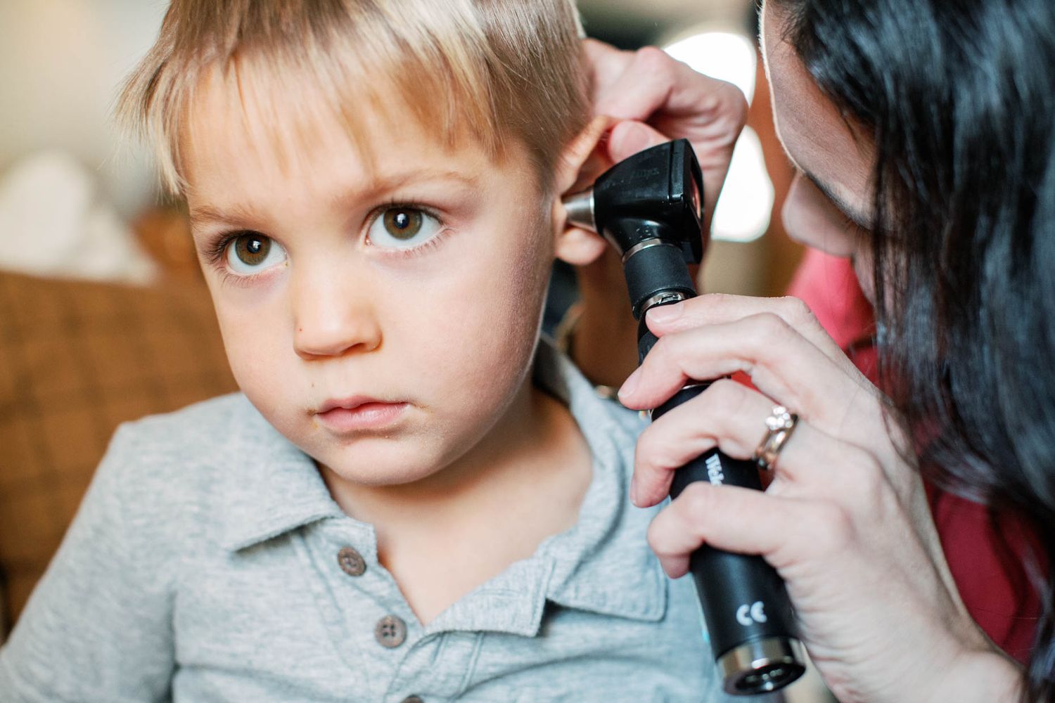 A doctor examines a young boys ear using an otoscope during a pediatric checkup.
