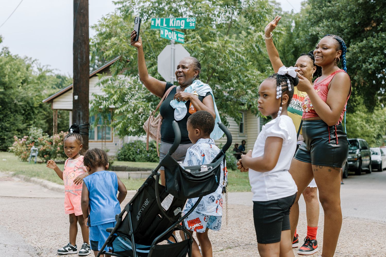 Group of people cheering and raising hands at a lively outdoor Juneteenth street celebration.