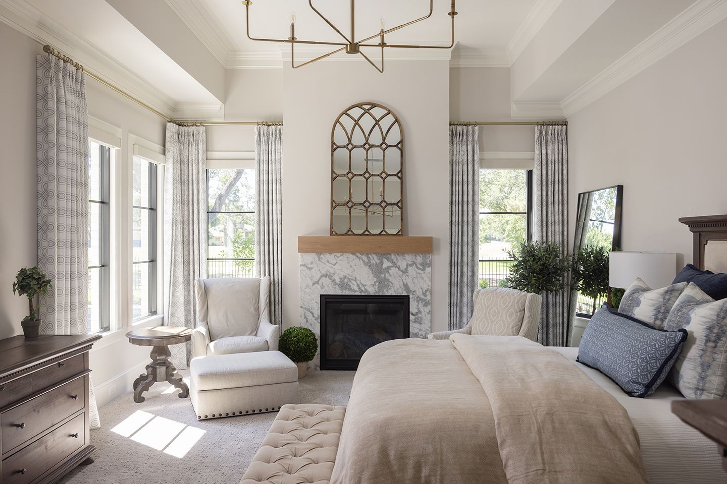 Elegant master bedroom with marble fireplace, vaulted ceilings, neutral tones and natural light.