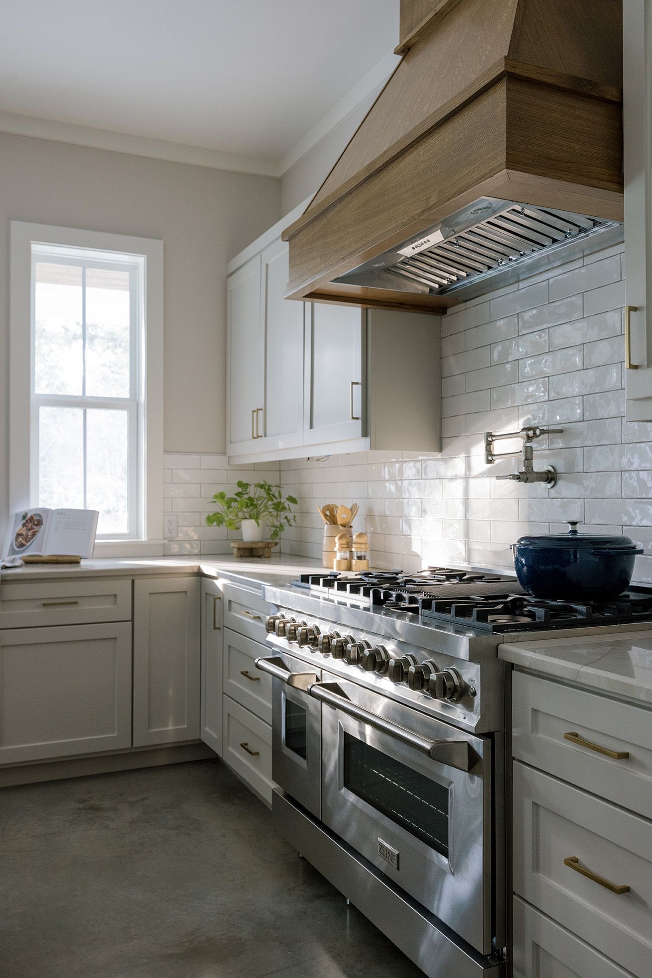 Classic white kitchen with professional stainless range, subway tile backsplash, and wood range hood.