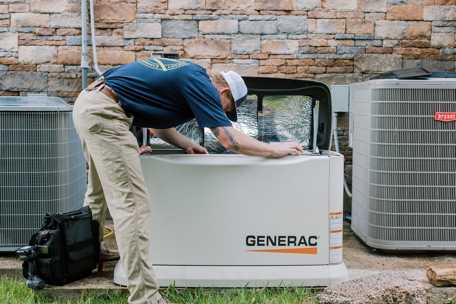 Technician servicing a Generac standby generator outdoors next to residential AC units.