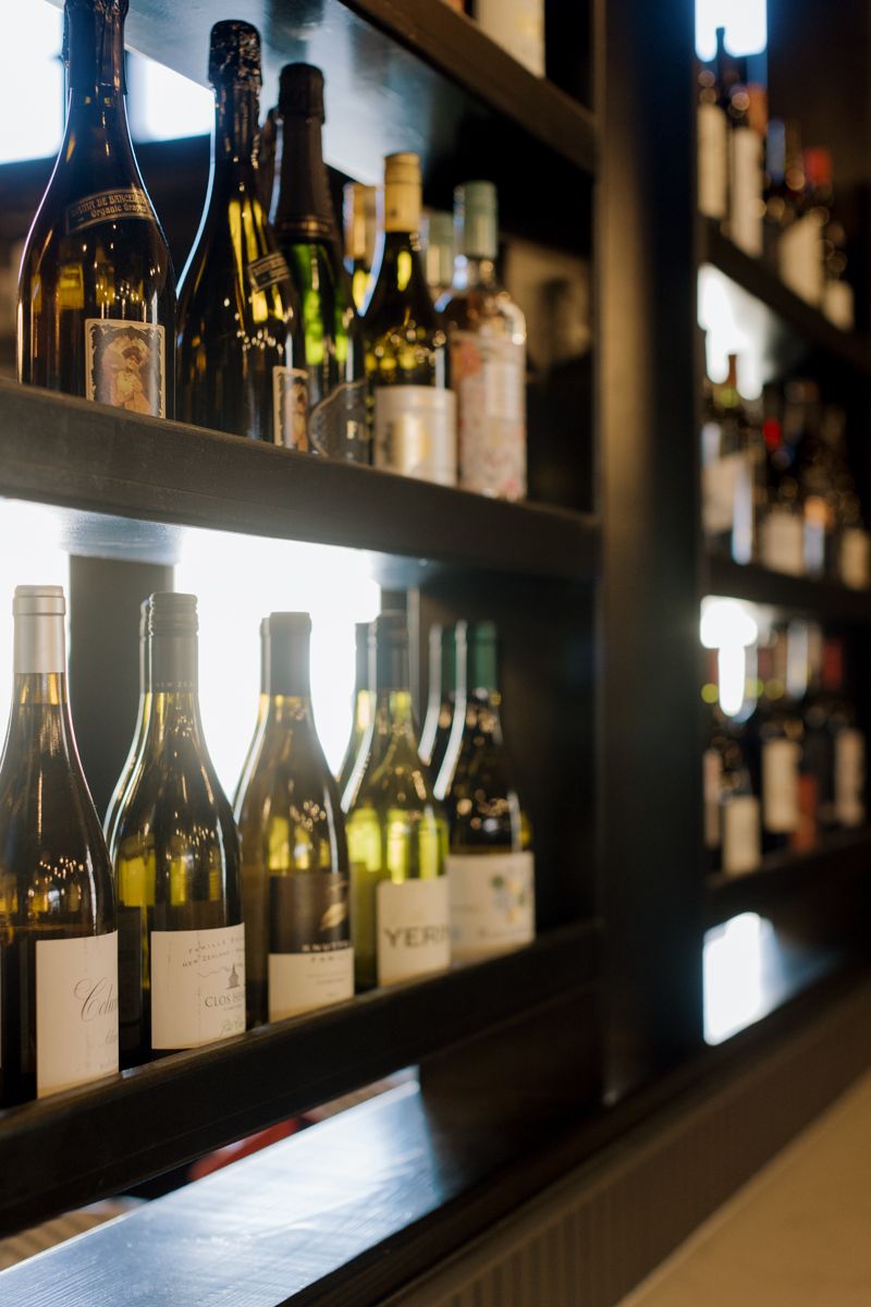 Elegant bar shelves displaying a curated selection of wine and spirit bottles with warm backlit lighting.