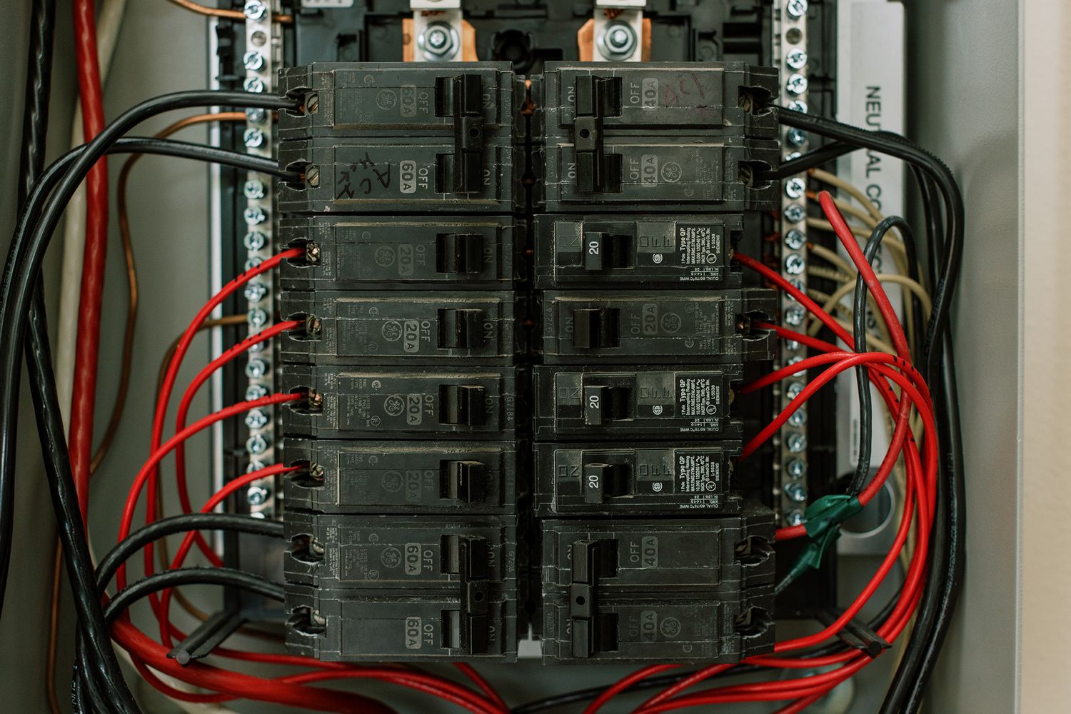 Residential electrical panel with circuit breakers, red and black wiring, showing organized home power distribution system.