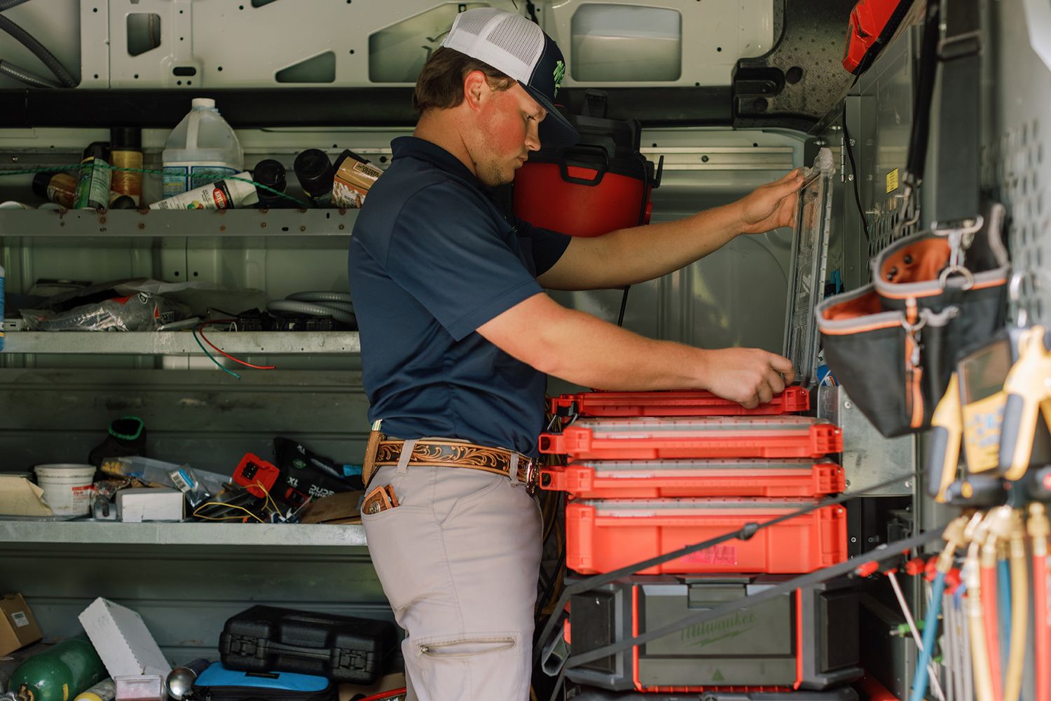 Malek service technician organizing red tool boxes in a fully equipped work van.