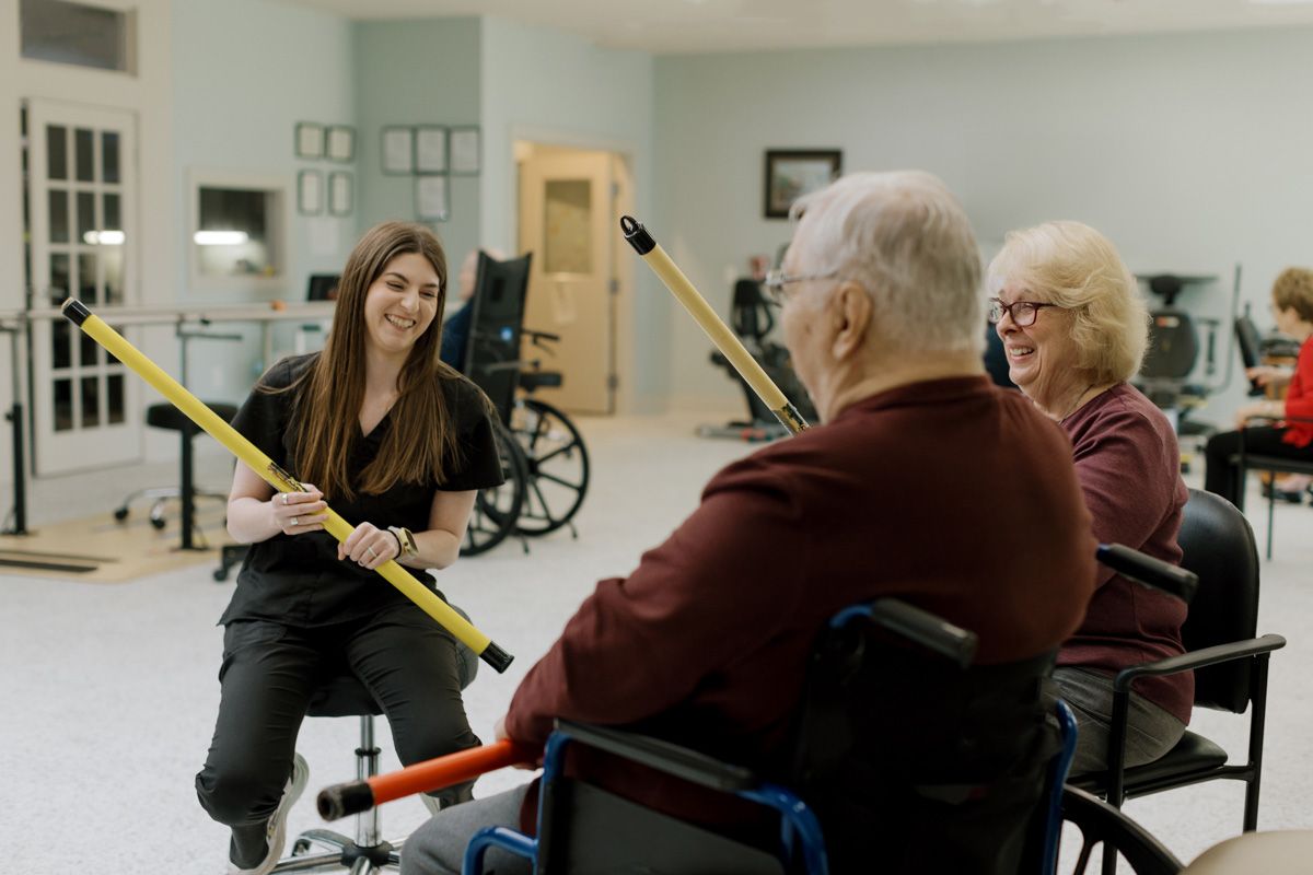 A physical therapist demonstrates exercise equipment to elderly patients in a rehabilitation center.