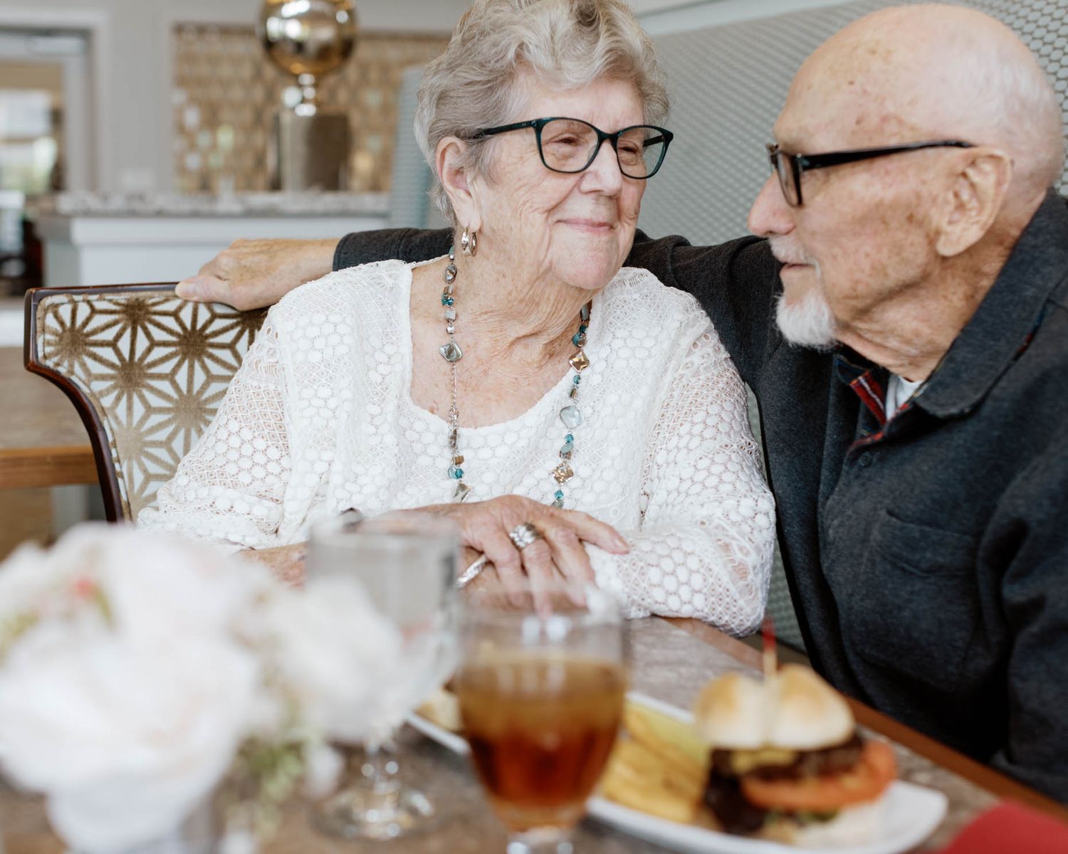 Elderly couple sharing a loving glance while dining together at table.