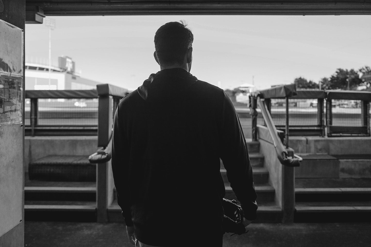 Silhouette of a man standing in a stadium tunnel holding a baseball glove.