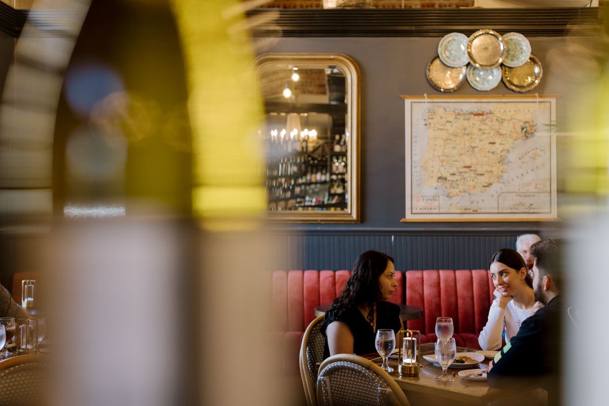 Two women dining in an elegant restaurant with red booth seating, a mirror, and decorative wall map.