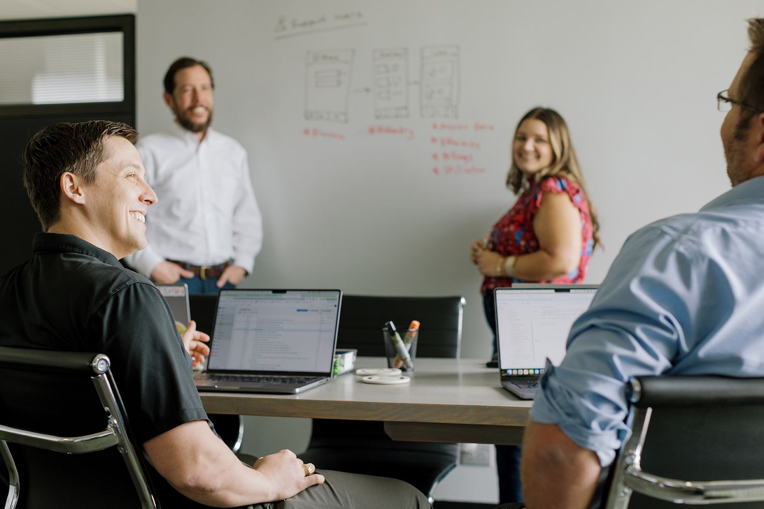 Four business professionals engaged in a collaborative meeting around a conference table in a modern office.