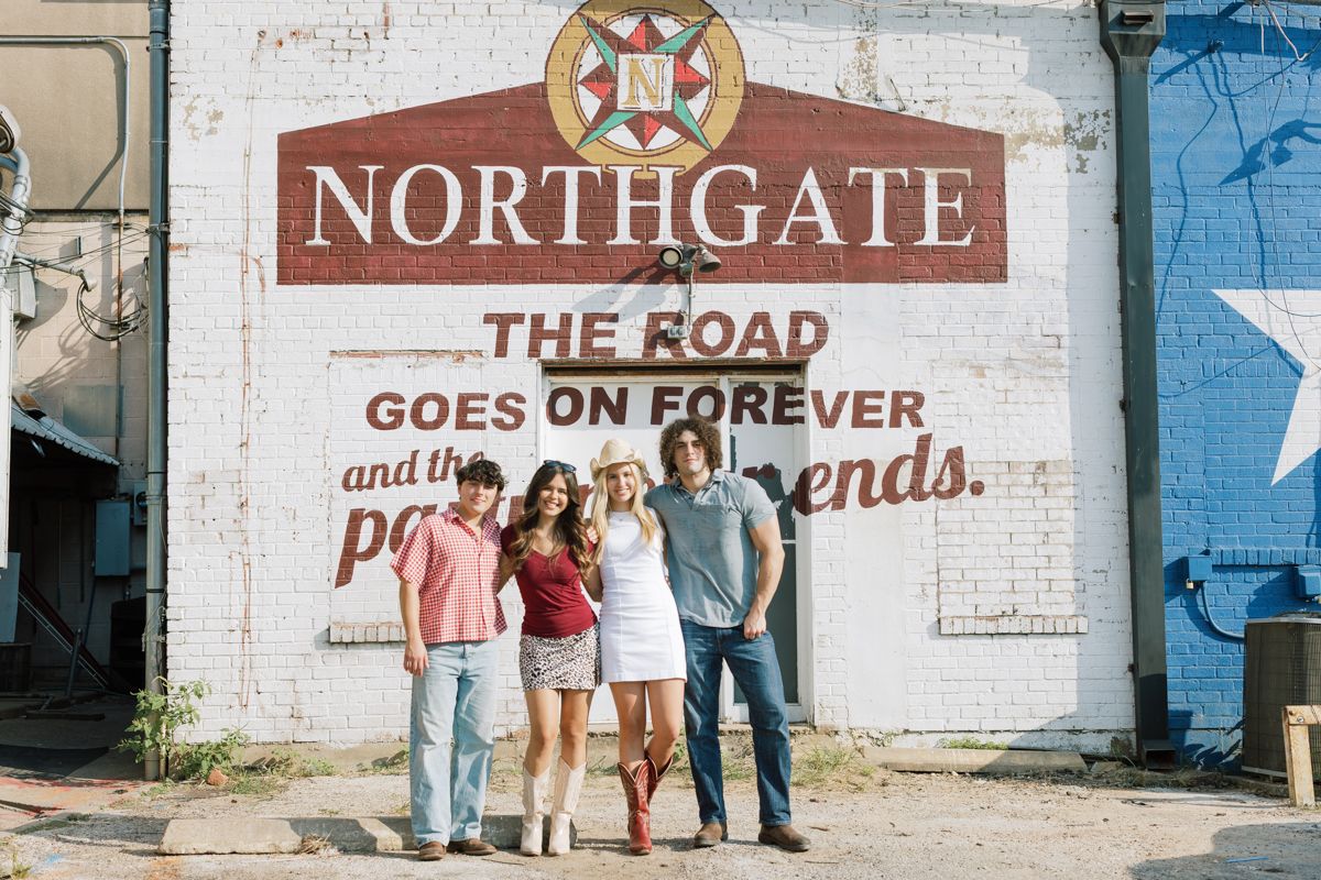 Four friends pose in front of the Northgate mural featuring the quote The Road Goes On Forever in Nashville.